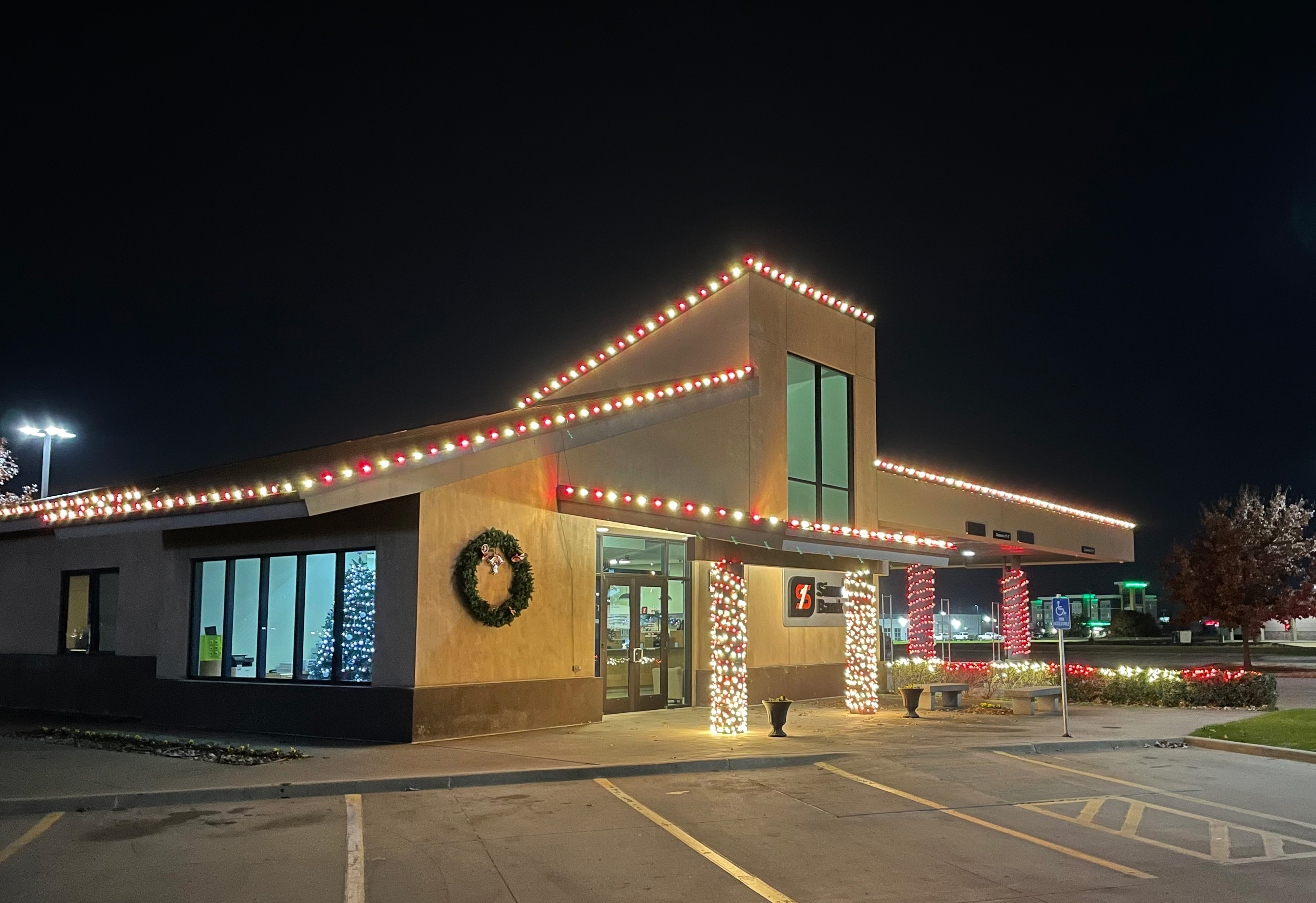 Commercial building with red and white roofline lights and fully wrapped entrance columns
